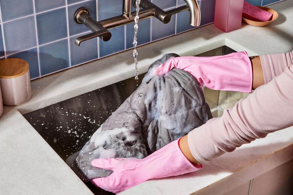 Person gently washing a weighted blanket in a tub with mild detergent